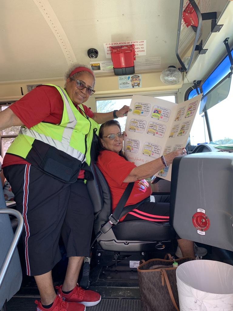 Bus drivers with thank you cards, smiling.